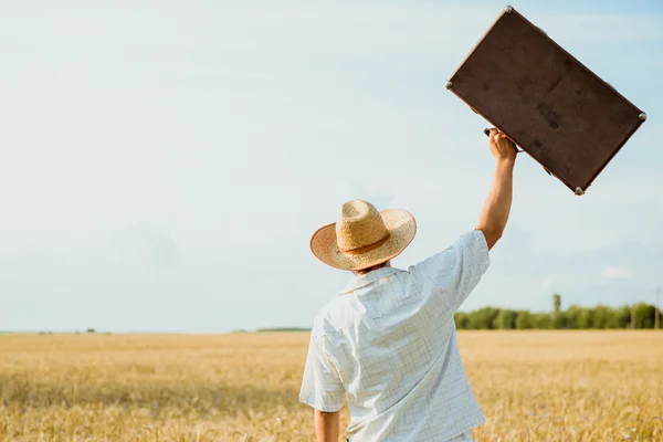 Hombre con sombrero de paja arrojando una maleta retro —  Fotos de Stock
