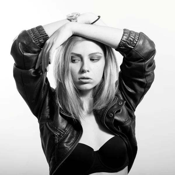 Sexi blonde girl in leather jacket posing emotionally and looking down over light copy space background, Black and white portrait — Stock fotografie