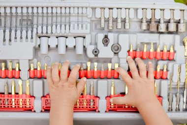 Young hands on drill bits. Closeup picture clipart