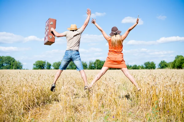 Back view of jumping high female and male holding hands together on the field outdoors copy space background — Stock Photo, Image