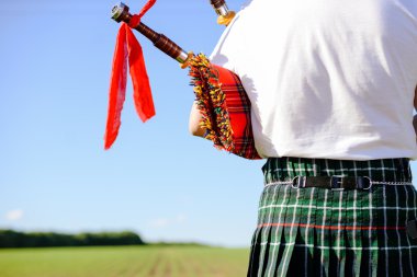 Male playing pipes on green summer outdoors background, closeup image 