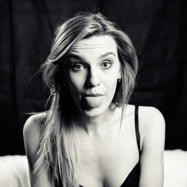 Black and white portrait of beautiful sexi blond young woman showing tongue out — Stock fotografie