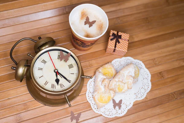 A coffee, two pastries, small present box and retro alarm clock — Stock Photo, Image