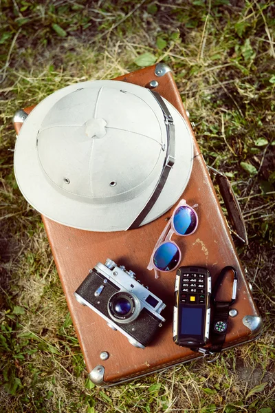 Top view of pithhelmet, camera, cellphone and sunglasses on suitcase — Stockfoto
