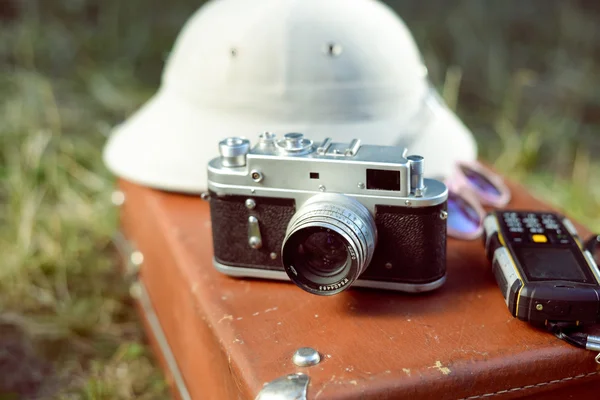 Closeup of pithhelmet, camera, cellphone and sunglasses on suitcase — Stockfoto