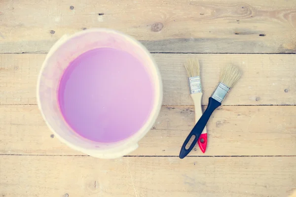 Color bowl with pink paint on wood board and two brushes — Stockfoto