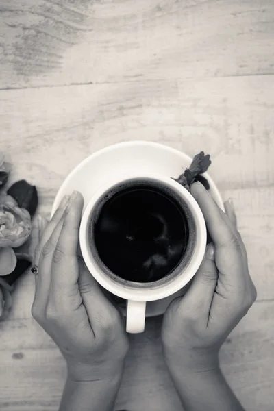 Black and white picture of hands embracing cup of coffee — Stock fotografie