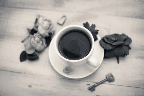 Black and white picture of cup of coffee and rose petals beside — 스톡 사진