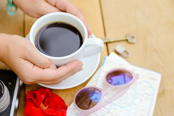 Closeup picture of hands holding cup of coffee on wooden table — Stock fotografie