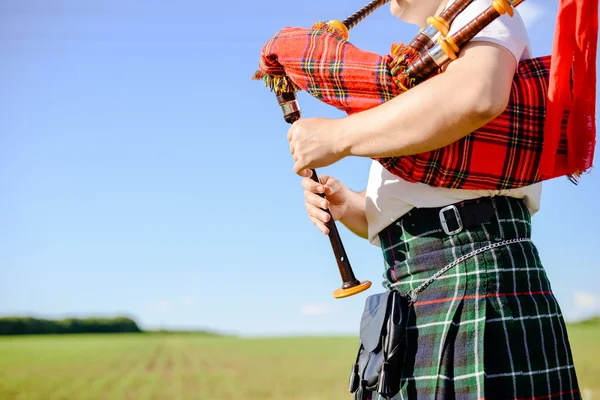 Männlich spielt schottische traditionelle Pfeifen auf grünem Sommer im Freien Hintergrund, Nahaufnahme Bild — Stockfoto