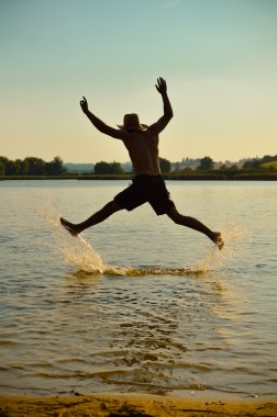 Genç adam sahilde eğlenmek için atlama