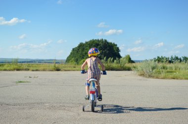 Child in a helmet riding bike on summer blue sky outdoors background copy space 