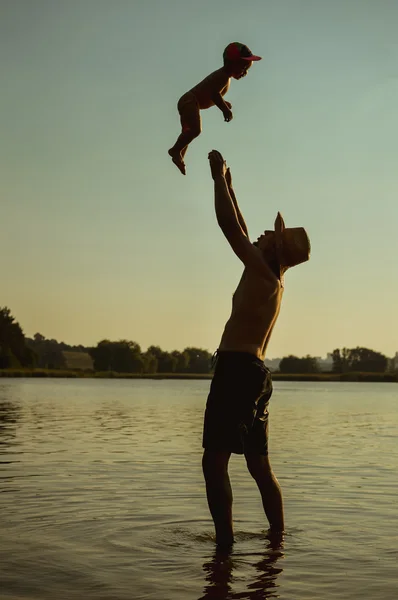 Feliz padre e hijo divirtiéndose en la playa de verano sobre el agua al aire libre fondo — Foto de Stock