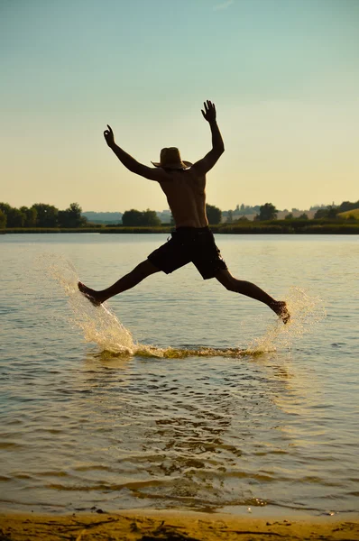 Genç adam sahilde eğlenmek için atlama