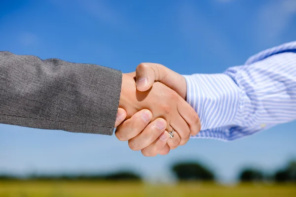 Business people handshaking on blue sky outdoors background, close-up picture — Stock Photo, Image