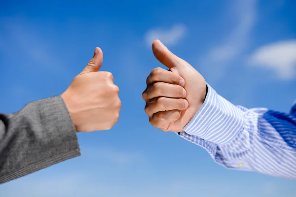 Close-up of business team holding their thumbs up. several human hands showing thumbs up against clear blue sky — Stock Photo, Image