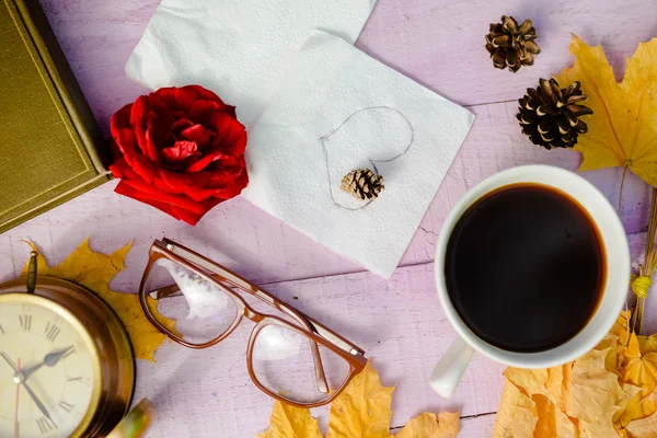 View from top on red rose, glasses, alarm clock, cup of coffee and napkin over wooden table background, close up picture — Stock Photo, Image