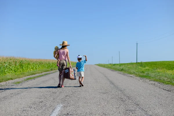 Силуэт женщины с детьми, идущими по сельской дороге на солнечном голубом небе на открытом фоне, скопировать космическое изображение — стоковое фото