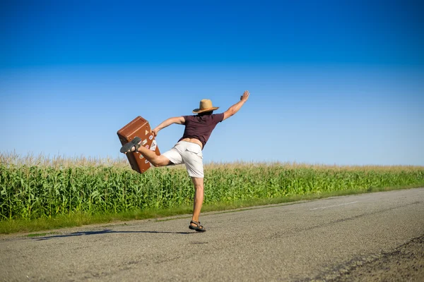 Bild von Mann mit Koffer eilt vorwärts und winkt Hand auf dem blauen Himmel grüne Wiese Sommer im Freien Hintergrund Kopierraum — Stockfoto