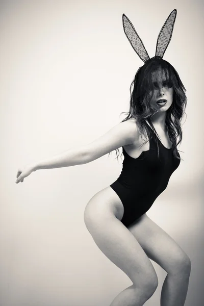Black and white portrait of sexy beautiful young lady having fun wearing bunny ears posing on light copy space background — Stock Photo, Image