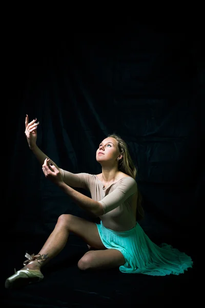 Retrato de una hermosa joven bailando sentada sobre un fondo negro — Foto de Stock
