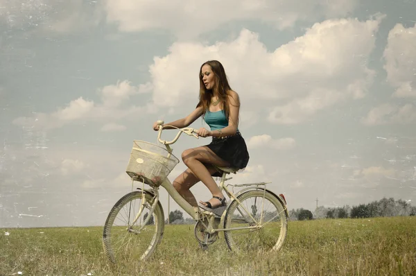 Joy of cycling: portrait of beautiful brunette young lady having fun in summer riding on bicycle on green field outdoors copy space background — ストック写真