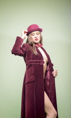 Sexy pretty girl in long coat wearing bowler hat and bow tie