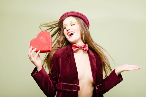Picture of sexy pretty young lady in elegant coat and bowler hat holding heart shaped present gift box — Stock Photo, Image