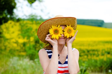 Young woman wearing straw hat with two sunflowers instead glasses