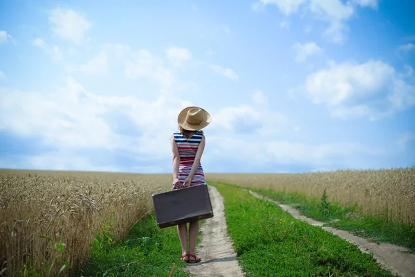 Огляд жінки з валізою на дорозі в пшеничному полі — стокове фото
