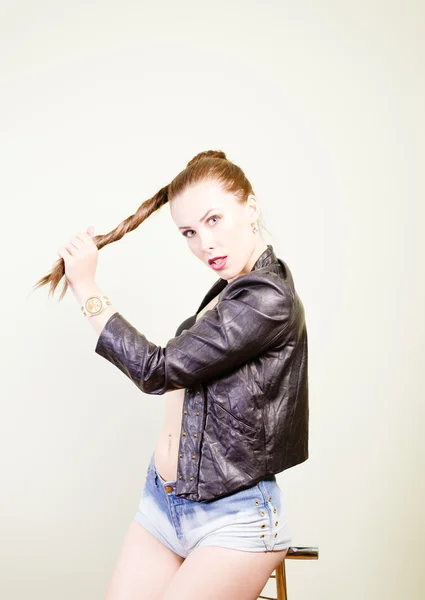 Girl wearing leather jacket and denim shirts sitting on chair — Stock Fotó