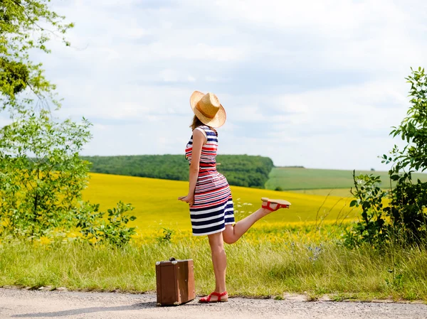 Picture of beautiful happy girl wearing dress and straw hat dancing on roadside — 图库照片