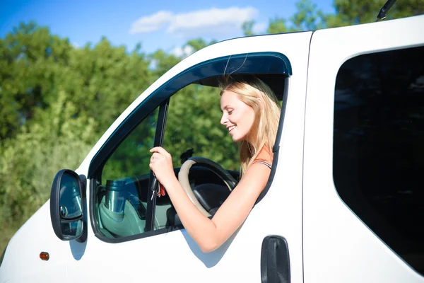 Portrait of happy blond woman driving white car and smiling — ストック写真