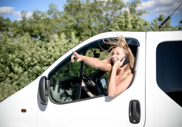 Chica rubia conduciendo coche hablando por teléfono móvil y mirando por la ventana — Foto de Stock