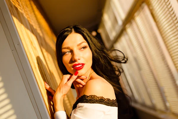 Aufregende junge Dame mit roten Lippen auf dem Balkon bei sonnigem Tag — Stockfoto