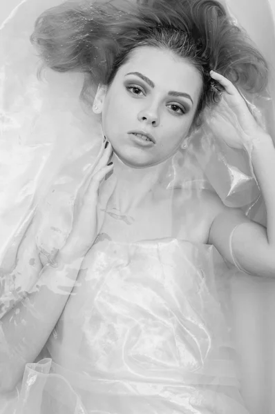 Black and white photography of beautiful blonde sexy young woman with red lips relaxing laying in a bath water and looking at the camera, closeup portrait — Stock fotografie