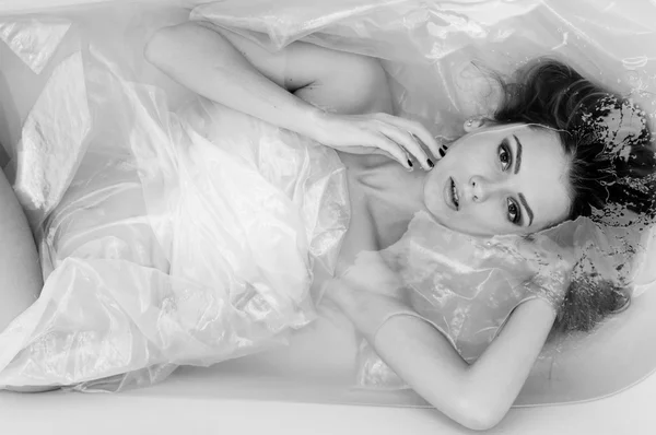 Beautiful sexy young woman relaxing laying in a bath water and looking at the camera closeup portrait. Black and white photography 