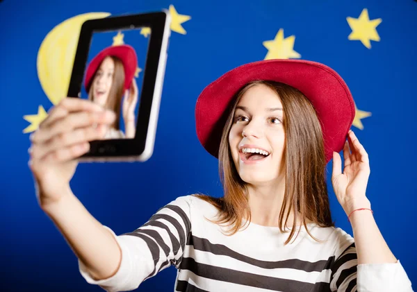 Молода щаслива жінка приміряє червоний капелюх і робить селфі — стокове фото