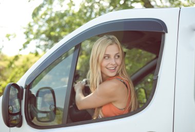 Young girl looking back from car window on countryside background