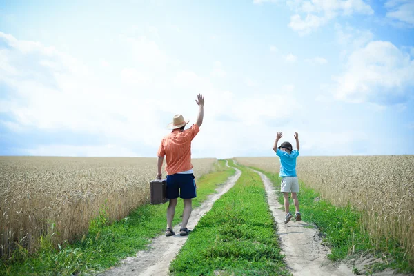 Travelling man and boy with old suitcase on country road — Stok fotoğraf