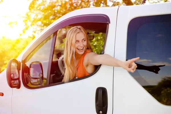 Chica bonita en el coche emocionado apuntando a algo en la carretera — Foto de Stock