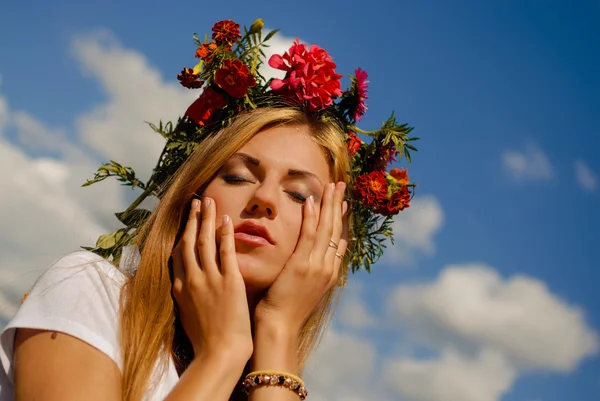 Stunning girl in flower wreath dreaming on blue sky background — Stock Photo, Image