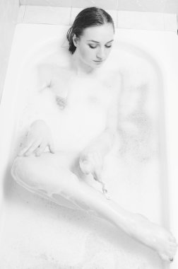 Picture of shaving legs beautiful young sensual lady having fun happy relaxing lying in spa bath on foam water copy space background. Black and white photography