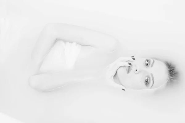 Black and white photography portrait of beautiful tender young lady lying in the milk water — Stock fotografie