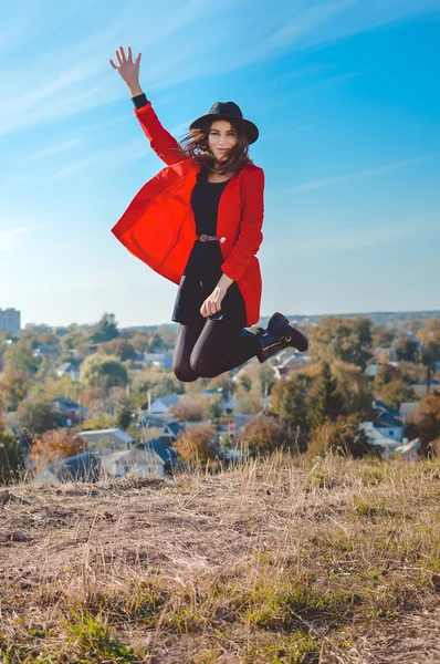 Garota excitada de chapéu preto pulando no fundo do campo de outono — Fotografia de Stock