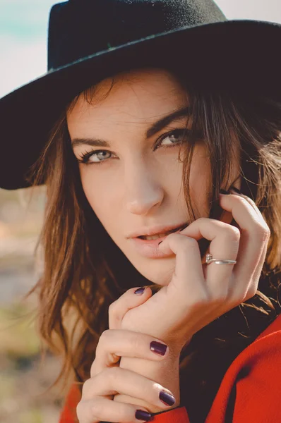 Hübsche Frau mit Hut blickt auf herbstlichen Hintergrund in die Kamera — Stockfoto