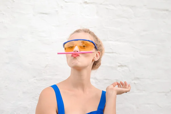 Funny girl wearing protecting glasses balancing with pencil on lips — Stock Photo, Image