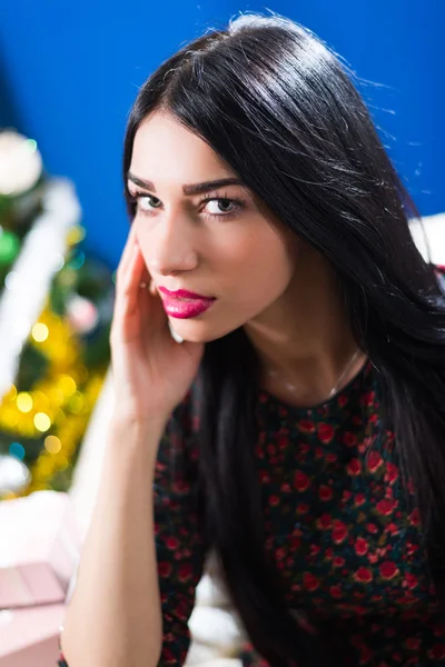 Senhora com cabelos longos olhando a sério no fundo de Natal desfocado — Fotografia de Stock