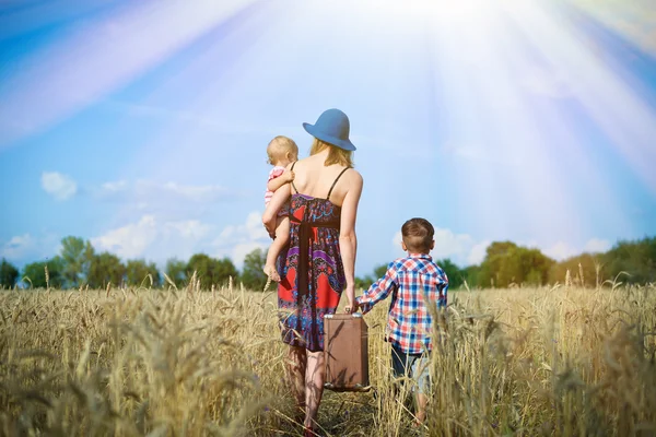 Image of woman wearing hat with baby girl walking away on wheat field.