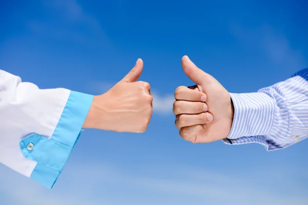 Thumb up between doctors over blue sky sunny outdoors background, closeup picture — Stock Photo, Image